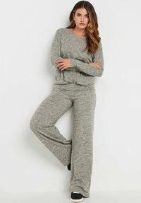 Grijs gebreid loungewearset met een relaxed-fit lange mouw top en wijde broekspijpen met een gestructureerde afwerking. Zwarte instap schoenen inbegrepen.
