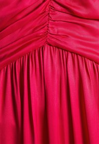 Ljust rosa satinfabric med samlade och rynkade detaljer som skapar veck och textur.