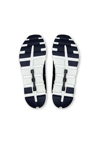 Chaussures de sport avec une semelle en caoutchouc marine foncé, présentant des accents blancs, une surface texturée et un design segmenté pour une meilleure adhérence.