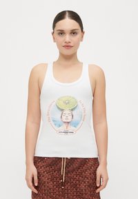 Top sin mangas blanco con una impresión gráfica de una mujer y una lima sobre su cabeza. Presenta texto enmarcado en naranja y azul, enfatizando un tema tropical.