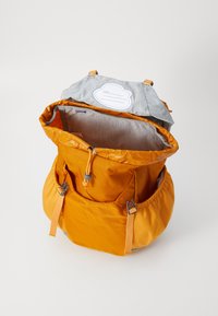 Orange backpack with drawstring closure and elastic side pockets. Interior features grey fabric lining and a label for naming.