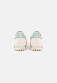 White sneakers with mint green accents, suede and mesh materials, round toe, and textured rubber outsole with a tread design.