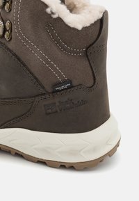 Brown hiking boot with a soft faux fur collar, Texapore label, and textured rubber sole featuring a zigzag pattern. Jack Wolfskin branding present.