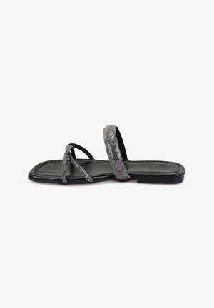 Strappy sandal featuring a black base with metallic silver accents, a flat sole, and a smooth texture. Open design with minimal coverage.