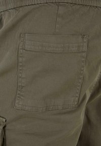 Men's cargo shorts in olive green fabric with a visible back pocket, plain texture, and contrasting stitching details.