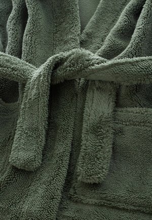 Žalias pūkuotas vonios chalatas su tekstūruotu, pūkuotu paviršiumi. Savybės: užrišamas uždarymas, sulenkta apykaklė ir kišenės priekyje.
