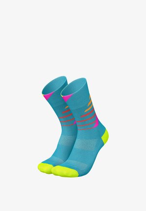 Mehrfarbige Socken haben eine türkisfarbene Basis mit leuchtend gelben Zehen und Fersen. Auffällige rosa und gelbe Streifen erzeugen ein dynamisches Muster.