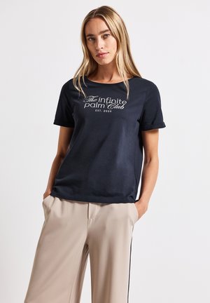 Navy short-sleeve t-shirt made of soft cotton, featuring a white graphic print text on the front. Paired with beige pants.