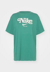 Zelené bavlněné tričko s krátkým rukávem, s velkým bílým logem "Nike" a textem "Since 1972", kulatým výstřihem a volným střihem.