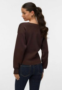 Bruine sweatshirt met een ronde hals, losse pasvorm en lange mouwen. G dragen met donkerblauwe jeans, zichtbaar vanuit een zijaanzicht en met gestructureerde stof.