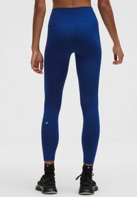 Blå leggings med hög midja gjorda av mjukt, elastiskt material, figurnära design med en liten logotypdetalj nära ankeln.