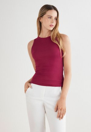 Vínový žebrovaný top bez rukávů s přiléhavým střihem, kulatým výstřihem, kombinovaný s bílými elegantními kalhotami.