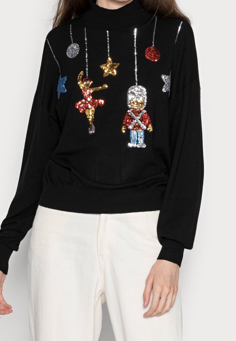 Pull noir avec des ornements suspendus en sequins : une ballerine, un soldat, des étoiles et des cercles colorés.