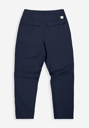 Donkerblauwe broek met een taps toelopend ontwerp, gemaakt van een gladde stof, met twee achterzakken en een klein labeldetail bij de taille.