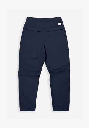 Donkerblauwe broek met een taps toelopend ontwerp, gemaakt van een gladde stof, met twee achterzakken en een klein labeldetail bij de taille.