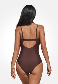 Brauner Einteiler-Badeanzug mit verstellbaren Trägern, offenem Rückenschnitt und glatter Textur. Mit minimalem Hardware-Akzent.