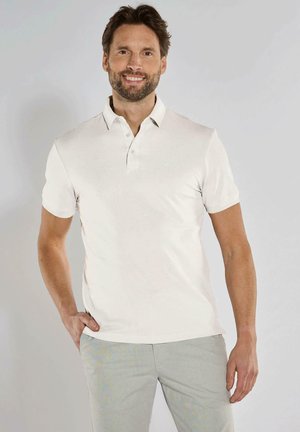 Kurzärmliges, hellbeiges Poloshirt aus glattem Baumwollstoff; ausgestattet mit einem klassischen Kragen und einem dezenten Logo auf der Brust.