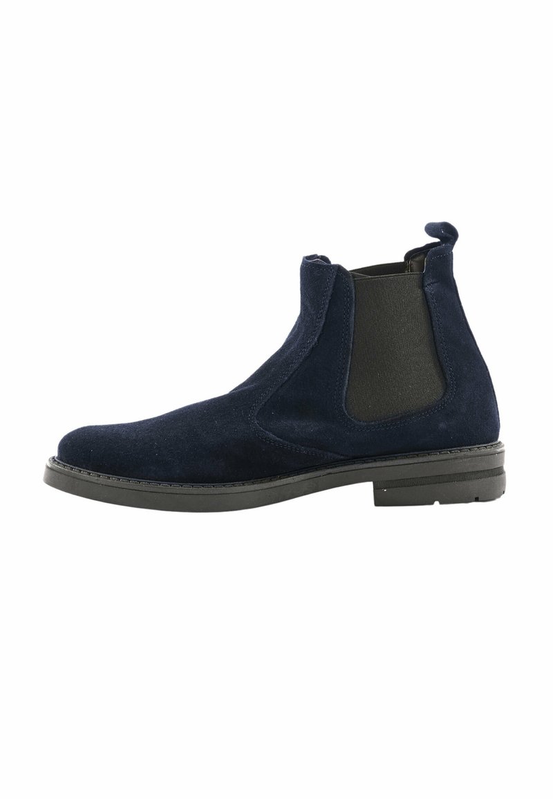 Stivaletti Chelsea in suede blu navy con pannelli laterali elastici, punta rotonda e suola in gomma nera. Presenta un tacchetto sul retro.