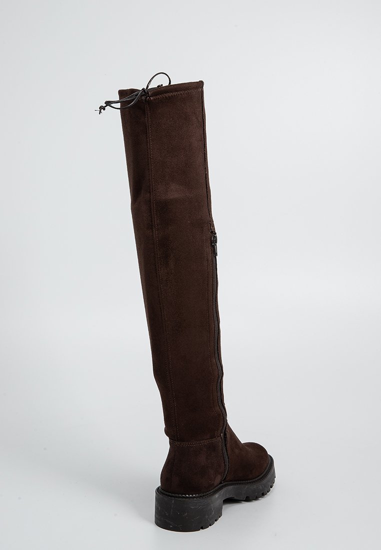Stivale in suede marrone alto fino alla coscia, con zip sul retro, punta rotonda e suola in gomma testurizzata. Presenta una parte superiore arricciata per una vestibilità sicura.