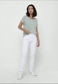 Stripet grønn og hvit kortermet t-skjorte sammen med hvite slim-fit jeans og hvite sneakers med sølvdetaljer. Enkelt, uformelt antrekk.