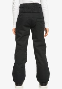Schwarze Schneehosen mit breitem Bund, Gesäßtasche und Roxy-Logo. Sie haben eine glatte Textur und eine lockere Passform und sind ideal für winterliche Aktivitäten.