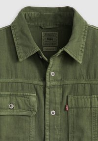 Camicia di denim verde con colletto a punta, tasche frontali, chiusure a scatto e finitura testurizzata. Presenta un'etichetta Levi's all'interno.