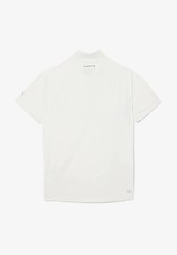 Hvid kortærmet polo skjorte, glat stof, ribbet krave, Lacoste-logo på ryggen, flad kant, minimalistisk design.