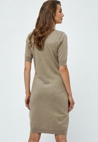 Robe tricotée beige, longueur genoux, avec des manches courtes, ourlet côtelé et texture lisse, présentant une silhouette ajustée et sans motifs visibles.