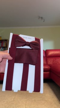 Bordo leptir mašna postavljena na bijelu karticu, s teksturiranom leptir mašnom i odgovarajućim podesivim trakama. Pogodno za formalne prigode.