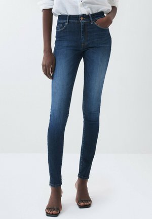 Jeans skinny en denim bleu foncé, dotés d'une taille haute, d'un design à cinq poches et d'un effet légèrement décoloré avec des accents brodés au niveau de l'ourlet.