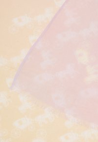 Silketørklæde med en lys rosa sektion med et gennemsigtigt udtryk, der ligger ovenpå en cremet baggrund med et gentaget mønster af kareter. Kanterne er frynset.