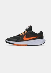 Černá sportovní bota s oranžovými akcenty a logem Nike, s prodyšným svrškem, polstrovanou podrážkou a texturovaným vzorkem pro lepší oporu.