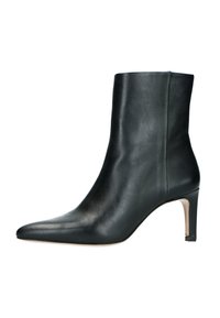 Bottine en cuir noir avec un bout pointu et un talon haut et fin. Texture lisse avec un design épuré et un subtil détail de surpiqûre sur le côté.