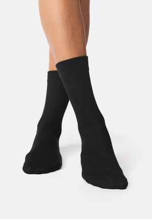 Black cotton ankle socks feature a smooth texture, ribbed cuff, and a fitted design, extending just above the ankle.