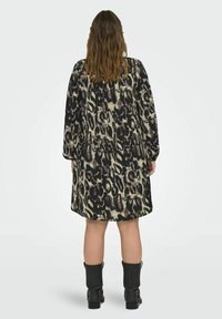 Šaty s leopardím potiskem v černé a béžové barvě, dlouhými rukávy, volným střihem a délkou po kolena. Nošeno s černými kotníkovými botami.