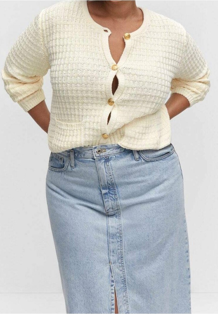 Cremefarbener, strukturierter Strick-Cardigan mit drei Knöpfen, kombiniert mit einem hellen Jeansrock mit Frontschlitz. Kurze, umgeschlagene Ärmel.