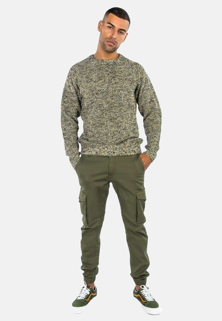 Maglione grigio textured, pantaloni cargo verdi con tasche e sneakers sportive verdi e bianche. Outfit casual mostrato su un modello maschile.
