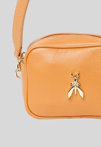 Borsa a tracolla in pelle arancione con finitura testurizzata, hardware dorato e un emblema decorativo a forma di insetto al centro.
