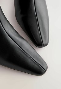 Sorte læder sko med spids tå og en glat overflade. Synlige sidesyninger langs den øverste kant. Slankt design med et minimalistisk udseende.