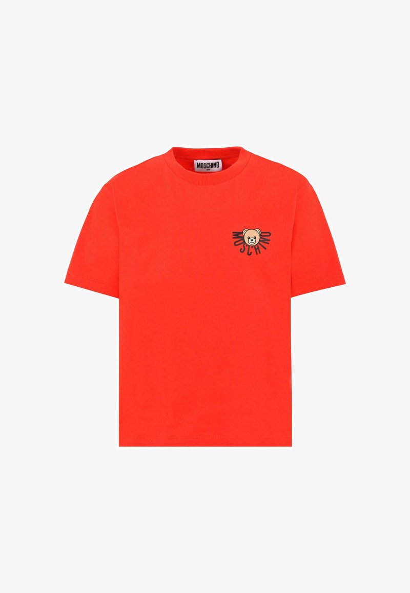 T-shirt en coton rouge avec un col rond. Présente un petit graphique d'ours sur la poitrine gauche et un design en texte noir "Moschino". Manches courtes.