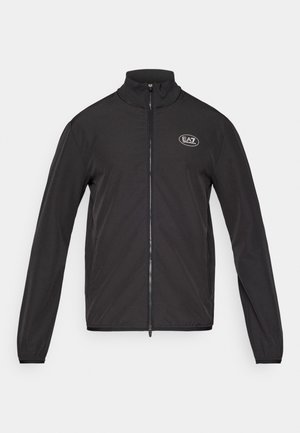 Veste noire zippée avec un col montant, fabriquée en tissu léger. Elle présente des manches longues et un petit logo EA7 sur le haut de la poitrine gauche.