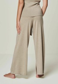 Beige weite Hosen mit einer weichen Textur und seitlichen Schlitzen, kombiniert mit einem passenden taillierten Oberteil im Rippdesign.