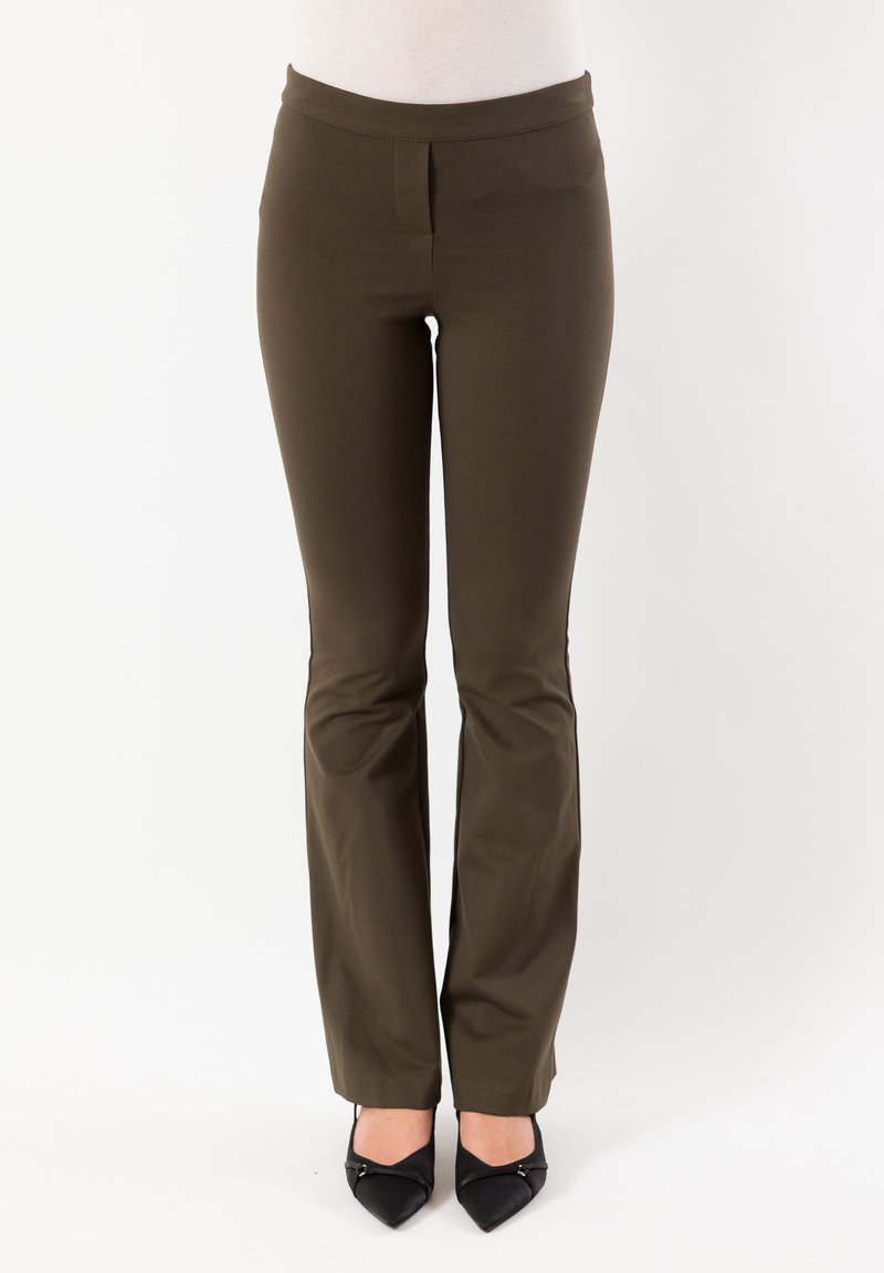 Pantaloni marroni su misura con vita aderente, tessuto morbido e leggero svasatura all'orlo, abbinati a tacchi neri a punta.