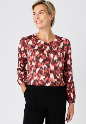 Bluse mit rotem und pinkem abstraktem Print, mit rundem Ausschnitt, langen Ärmeln mit gerafften Bündchen und drei dekorativen Knöpfen vorne.