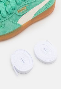 Baskets en daim turquoise avec logo PUMA blanc, dotées d'une semelle en caoutchouc naturel. Deux lacets blancs ronds placés sous la chaussure.