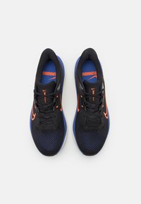 Fekete sportcipők, hálós felsőrésszel, kék részletekkel, narancssárga Nike logóval és fekete fűzőkkel, fehér háttéren.
