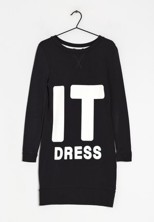 Robe décontractée noire à manches longues suspendue sur un cintre noir, avec un grand texte blanc indiquant « IT DRESS » sur le devant, sur fond blanc.