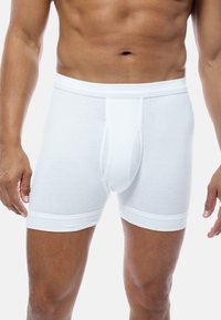 White ribbed boxer shorts with a fitted design, featuring an elastic waistband and a front opening. Smooth texture, knee-length style.