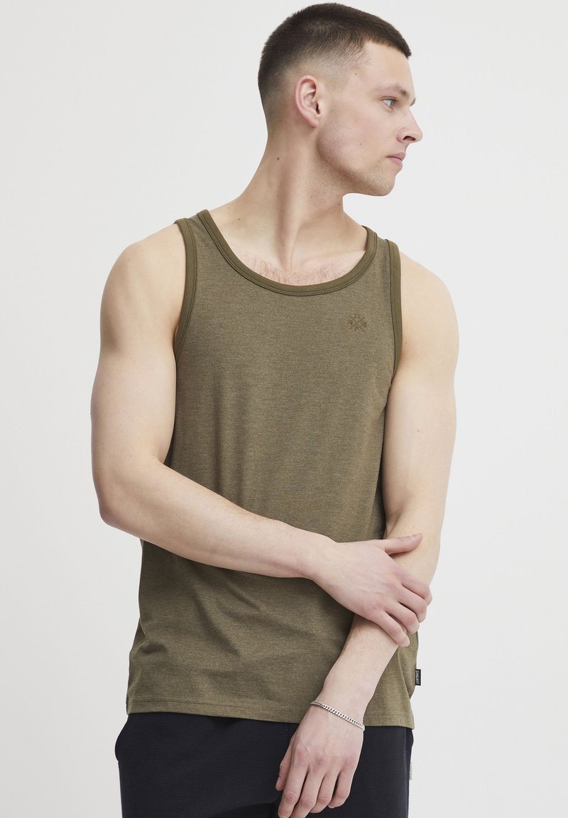 Olive green cotton tank top with a round neckline, subtle texture, and a small logo detail. Fits close to the body with no sleeves.