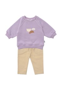 Lila Sweatshirt mit einem Grafikdruck von einer Tasse und einem Croissant, kombiniert mit hellbeigen Cordhosen, die einen elastischen Bund haben.